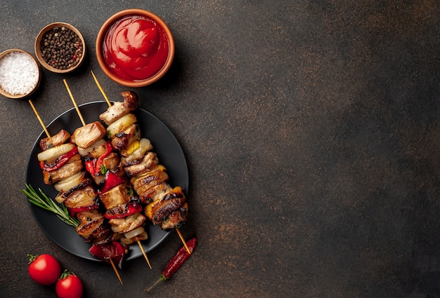 Brochettes de viande avec des légumes grillés sur une plaque sur un fond de pierre