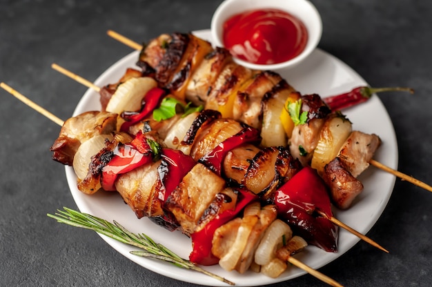 Brochettes de viande avec des légumes grillés sur une plaque sur un fond de pierre