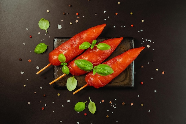 Photo des brochettes de viande de poulet crue marinée fraîche sur un fond noir en haut de l'espace de copie