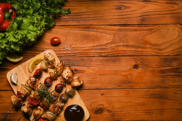 Brochettes de viande de poulet grillées avec des légumes frais sur une table en bois rustique noire