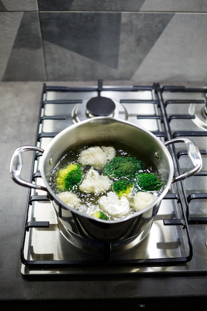 Brocoli et chou-fleur bouillis dans une casserole grise sur une cuisinière à gaz