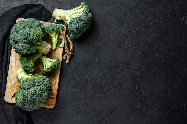 Brocoli cru dans un bol en bois. Mur noir. Vue de dessus. Espace pour le texte.