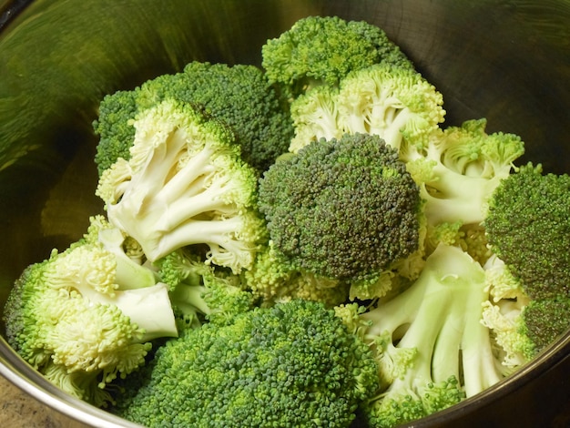 Brocoli cru frais dans une casserole en métal sur des fleurons de brocoli de fond foncé prêts pour la cuisson