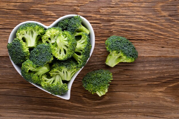 Brocoli frais dans un bol en forme de coeur sur un fond en bois