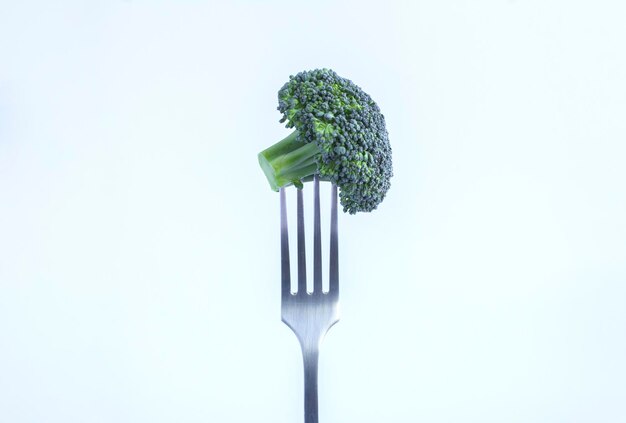 Brocoli poignardé sur une fourchette en argent sur fond blanc Espace de copie libre