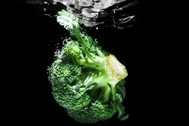 Brocoli vert frais tombé dans l'eau isolée