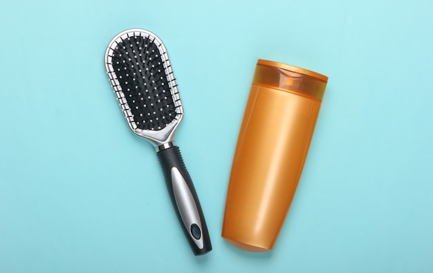 Brosse à cheveux avec bouteille de shampoing sur pastel bleu. Soin des cheveux. Hygiène