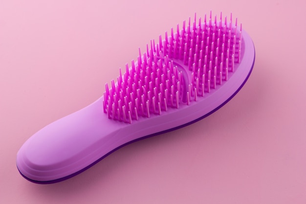 Brosse à cheveux en plastique sur fond rose