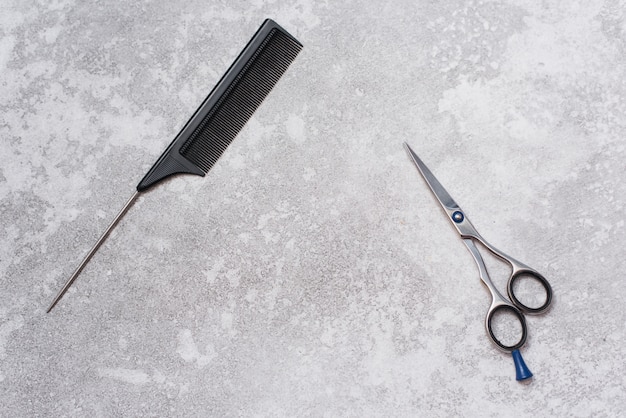 Une brosse à cheveux pour se séparer et des ciseaux pour couper les cheveux sur un gris grunge Copyspace