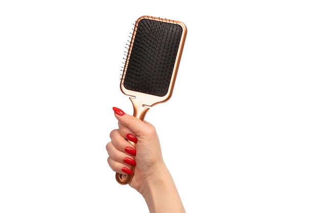 Une brosse à cheveux rouge dans la main de la femme avec des ongles rouges isolés sur fond blanc