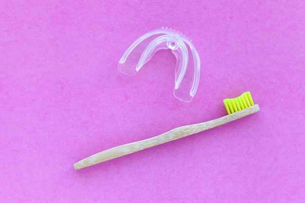 Photo brosse à dents en bambou. . accélérateur de blanchiment des dents. système de blanchiment dentaire espace de composition à plat pour le texte sur fond rose, vue de dessus