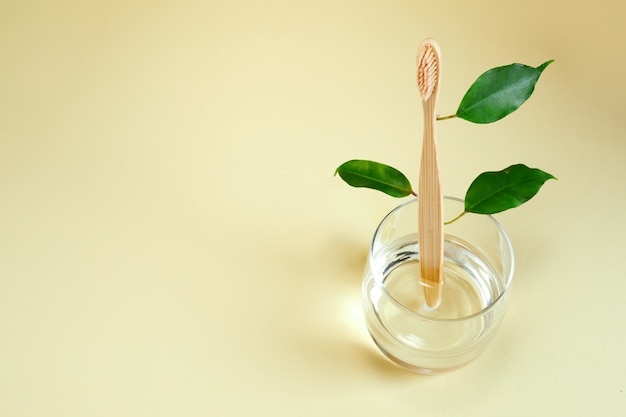 Brosse à dents en bambou en bois avec des feuilles sur verre. Zéro déchet, concept écologique. La vie sans plastique