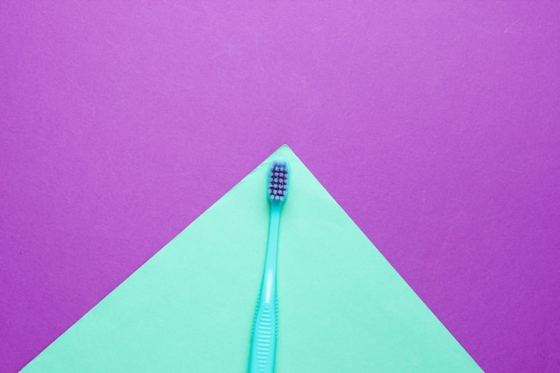 Brosse à dents bleue sur papier violet et bleu