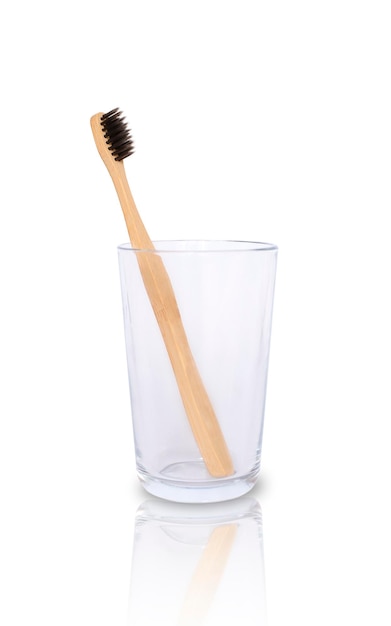 Brosse à dents en bois dans un bécher en verre sur fond blanc