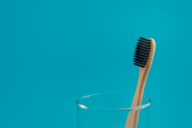 Brosse à dents en bois sur fond bleu dans une tasse