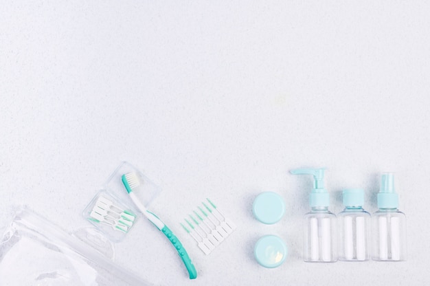 Brosse à dents et contenants en plastique pour les voyages sur fond blanc et baguettes. Pose à plat