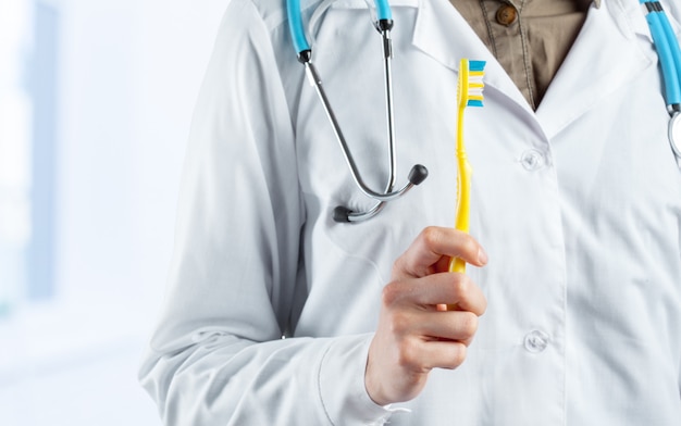 Photo brosse à dents dans les mains du médecin dentiste