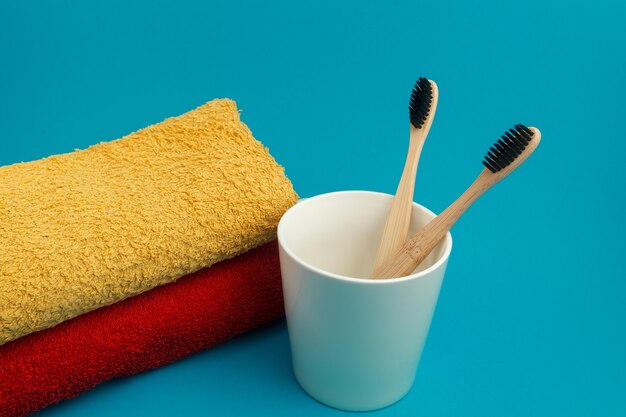 Brosse à dents dans un verre avec une serviette sur fond bleu