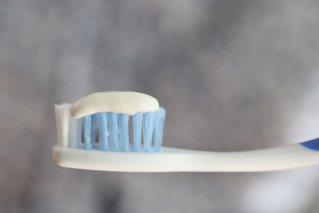 Brosse à dents et dentifrice gros plan sur fond flou gris