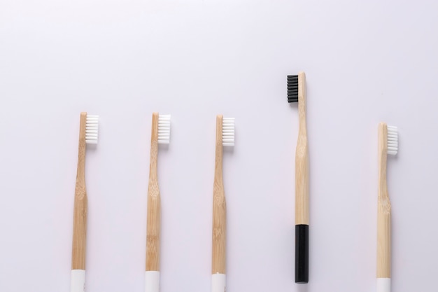 Une brosse à dents écologique noire s'envolant des autres brosses à dents blanches sur fond de mur blanc. Unique, penser différemment, individuel et se démarquer du concept de foule, orientation horizontale