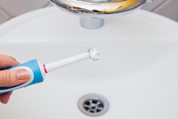 brosse à dents électrique avec dentifrice sur l'évier de la salle de bain