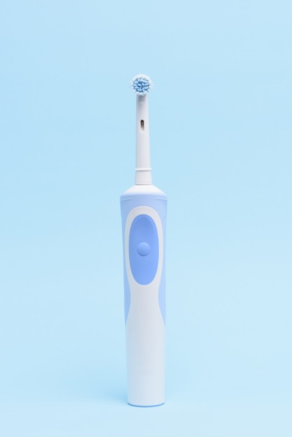 Une brosse à dents électrique isolée sur fond bleu clair.