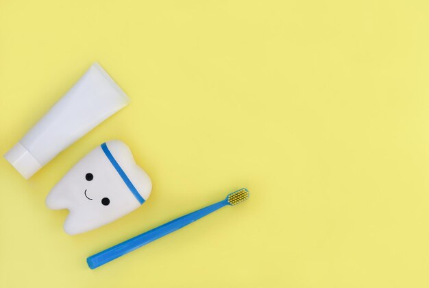 brosse à dents jouet et dentifrice sur fond jaune affiche pour le bureau de dentiste de stomatologie ou la clinique de soins dénaux pour enfants espace de copie d'hygiène buccale pour la publicité ou le texte