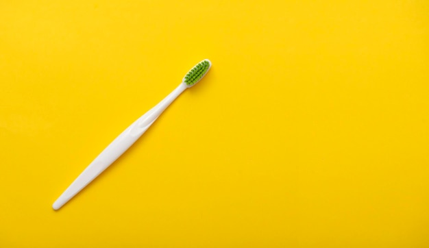 Brosse à dents en plastique blanc sur fond jaune vif comme espace de vue de dessus à plat pour le texte