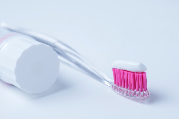 Brosse à dents rose et dentifrice sur fond blanc