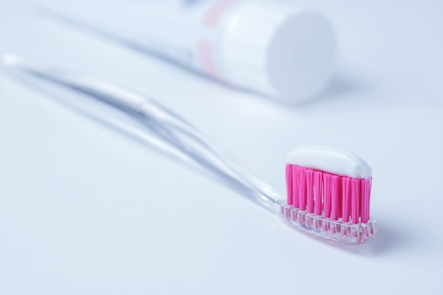 Brosse à dents rose et dentifrice sur fond blanc