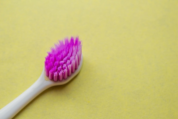 Photo une brosse à dents rose avec un manche blanc sur fond jaune.