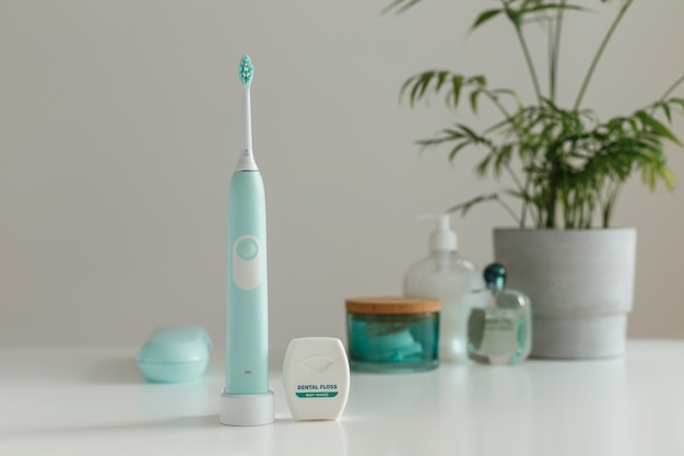 Brosse à dents à ultrasons électrique sans fil avec soie dentaire debout dans la salle de bain