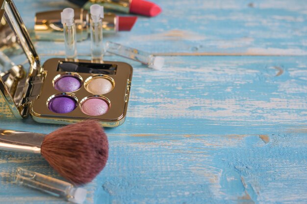 Brosse et un ensemble de cosmétiques pour femmes sur une table en bois bleue.