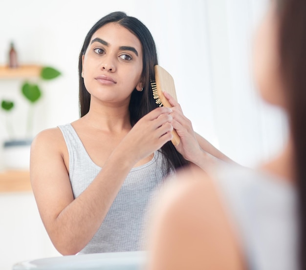 Cette brosse est la clé de la plénitude rebondissante Photo d'une jeune femme se brossant les cheveux devant le miroir