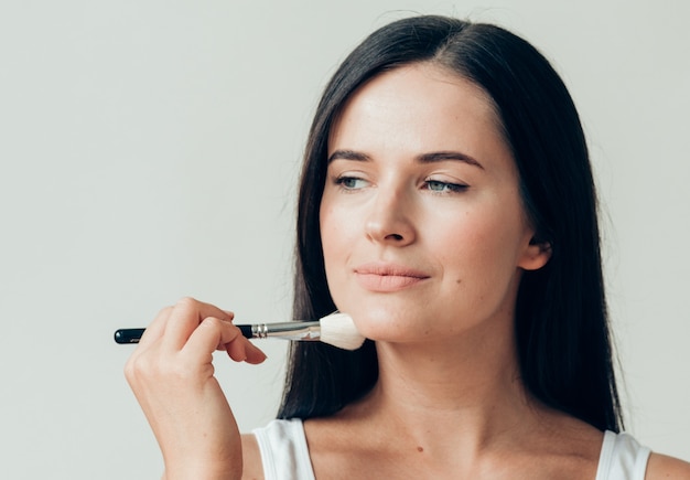 Brosse maquillage femme visage peau saine poudre de maquillage naturel. Prise de vue en studio.