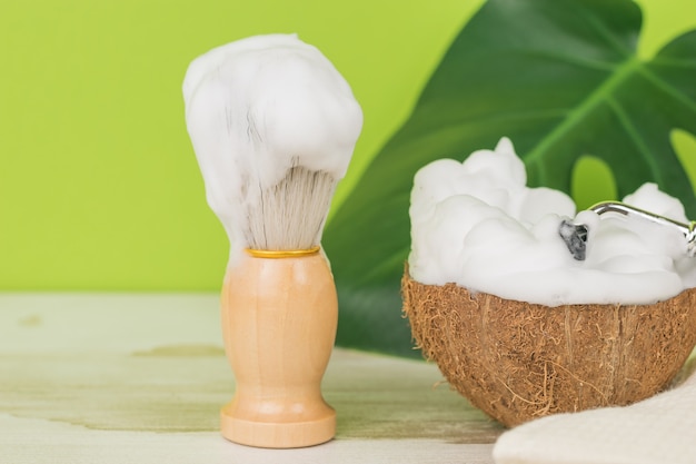 Une brosse et une mousse à raser épaisse dans un bol en noix de coco.