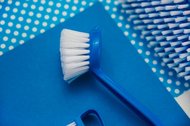 Brosse de nettoyage en gros plan sur fond bleu Une brosse avec un poil blanc et une poignée bleue Un équipement pratique pour nettoyer la maison