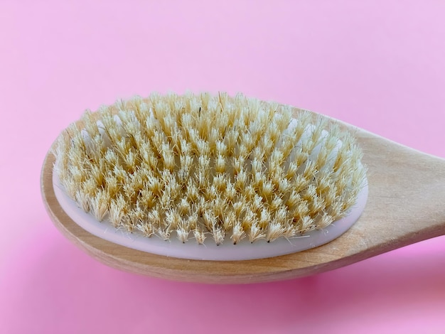 Brosse avec une poignée pour un massage anticellulite sec ou un brossage sur fond rose Concept de beauté