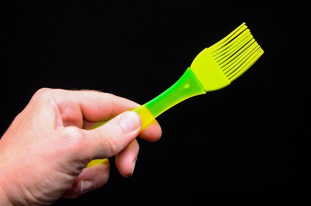 Brosse en silicone de cuisine verte sur fond noir