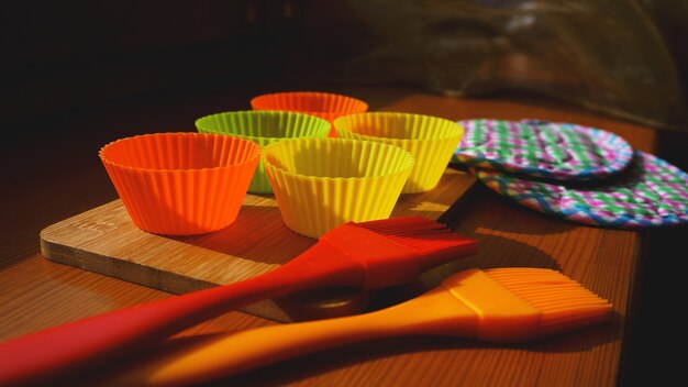 Brosse en silicone et doublures de cupcakes sur table en bois. Concept de cuisine et de cuisson sur fond de bois