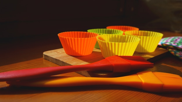 Brosse en silicone et doublures de cupcakes sur table en bois. Concept de cuisine et de cuisson sur fond de bois