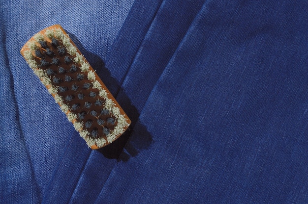 Une brosse à vêtements repose sur un jean plié.