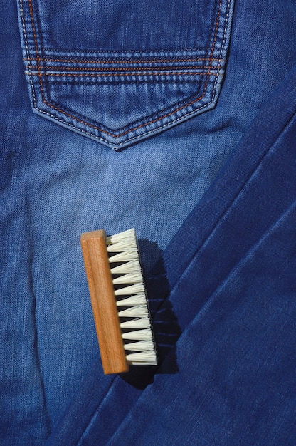 Une brosse à vêtements repose sur un jean plié.