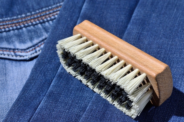 Une brosse à vêtements repose sur un jean plié.