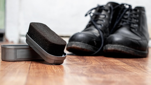 Brosses et chaussures noires de cirage de chaussure sur le plancher en bois