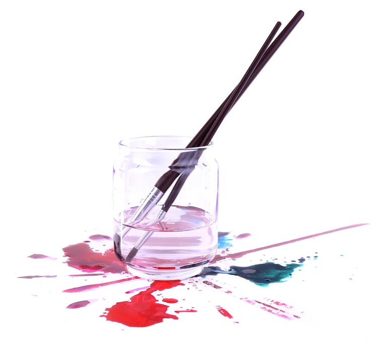 Photo brosses dans un bocal en verre avec de l'eau et des peintures renversées isolées sur blanc