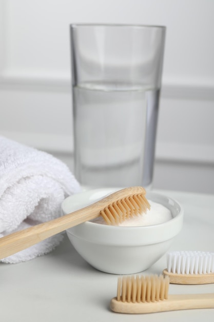 Brosses à dents en bambou bol de serviette de bicarbonate de soude et verre d'eau sur tableau blanc