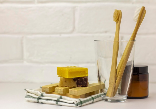 Brosses à dents en bambou écologiques dans un bécher en verre, poudre de dent naturelle et savon artisanal biologique, espace de copie.