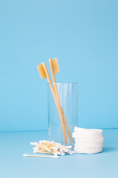 Brosses à dents en bambou sur fond bleu dans un verre de produits de soins personnels respectueux de l'environnement pour les personnes