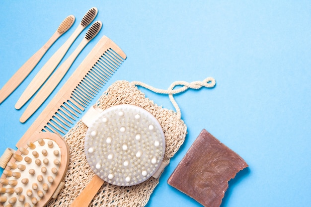 Brosses à dents en bambou, peigne en bois, gant de toilette tricoté, masseur corporel, savon naturel fait maison et brosse de massage à sec sur une surface bleue